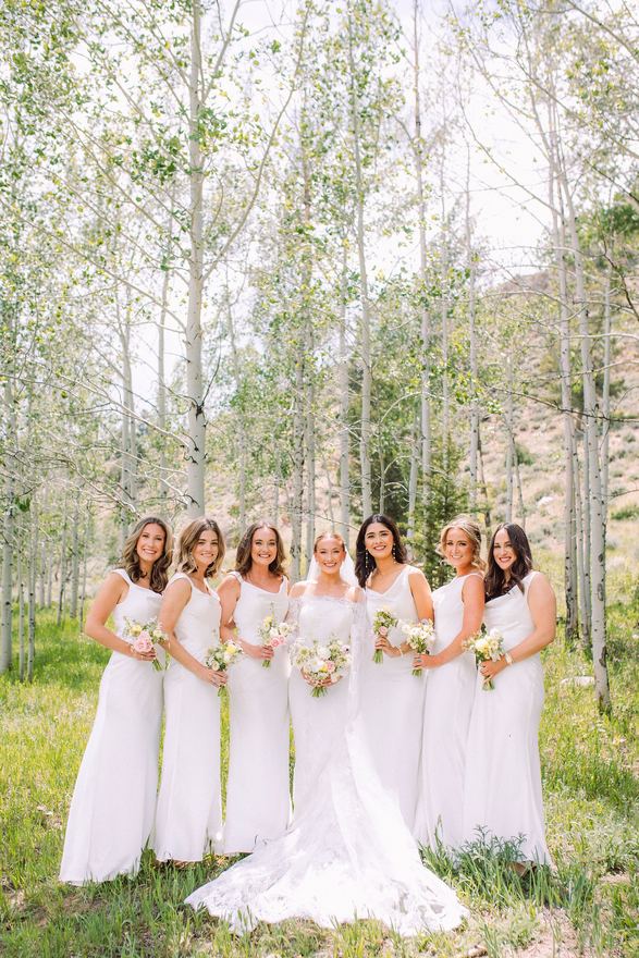 Bride and bridesmaids in white in an aspen grove