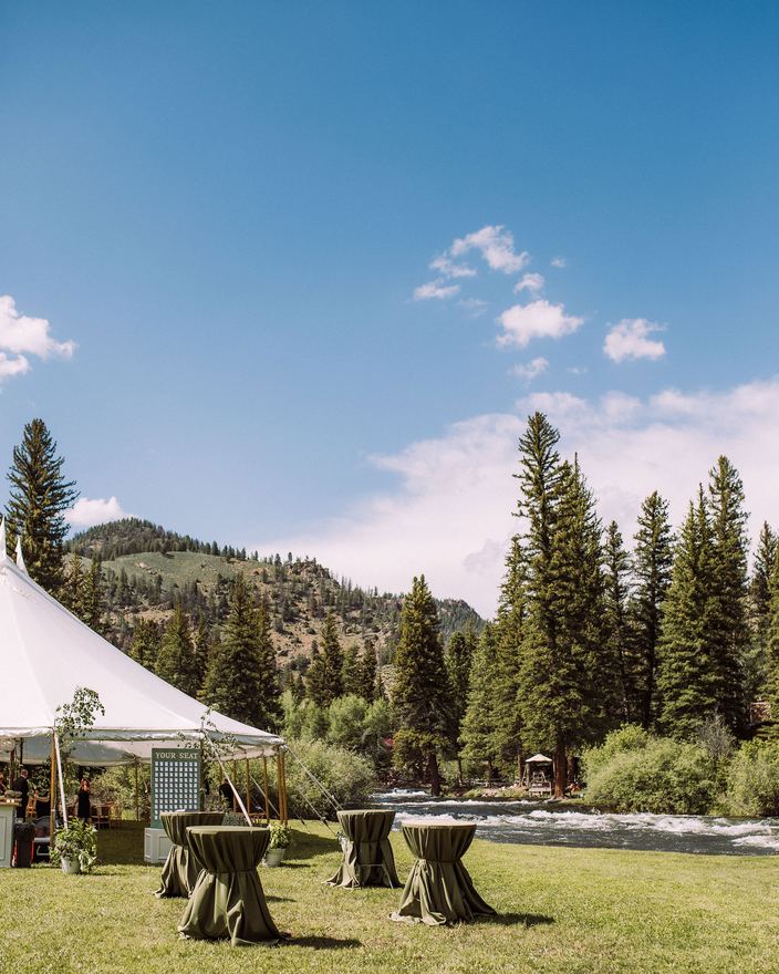 Cocktail tables on the lawn beside a sailcloth tent