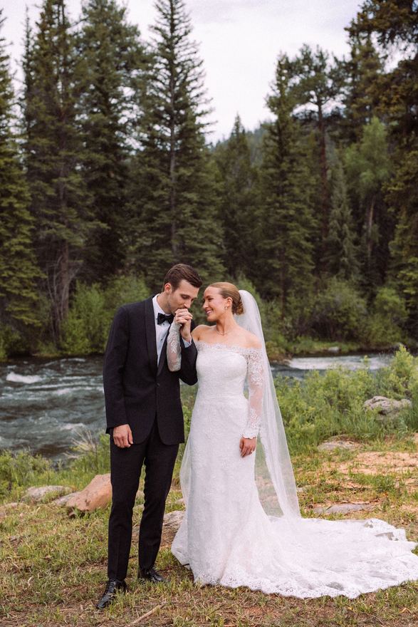 Groom kissing the bride's hand beside the Taylor River