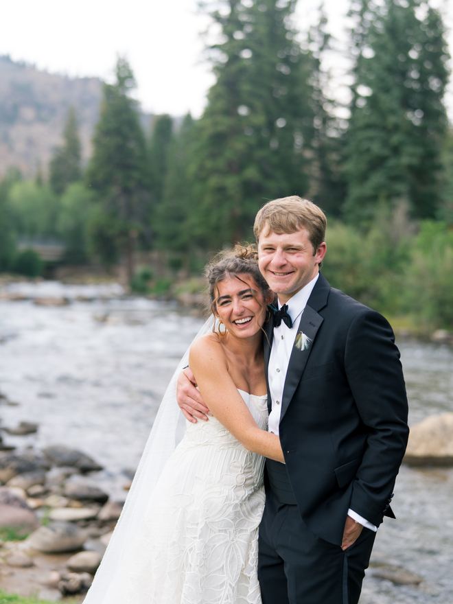 Bride and groom embracing on the riverbank