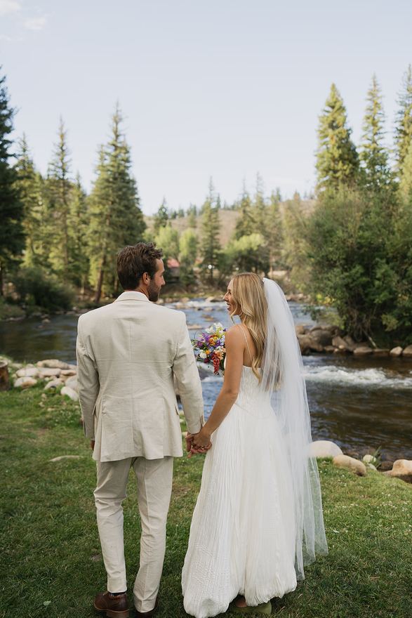 Bride and groom holding hands on the bank of the Taylor River
