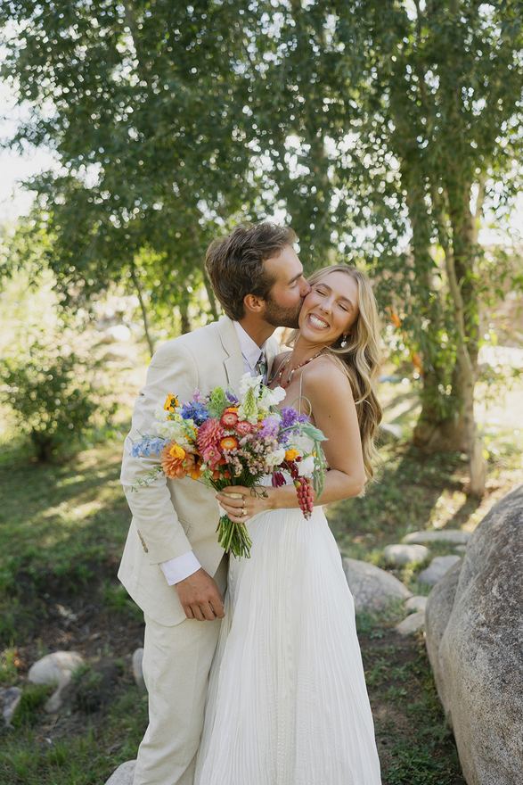 Bride and groom kissing, holding a colorful bouquet