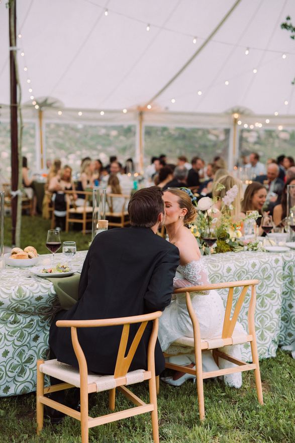 Bride and groom sharing a kiss at a reception table