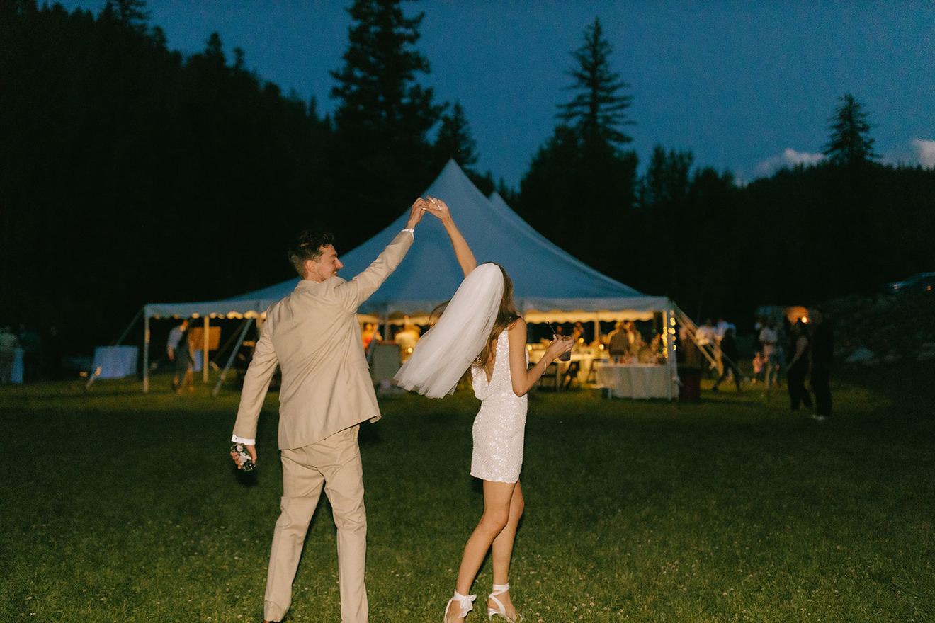 Bride and groom dancing on the lawn at dusk in front of the reception tent