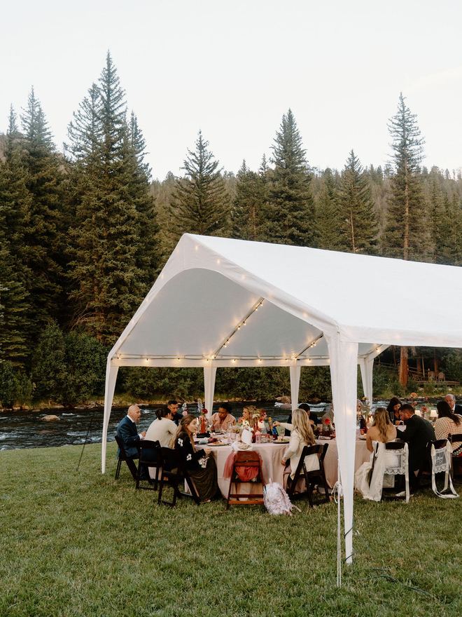 Guests at dinner under a frame tent by the river