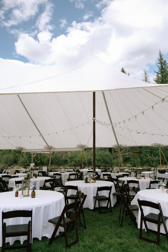 Reception tables with white linens under a sailcloth tent