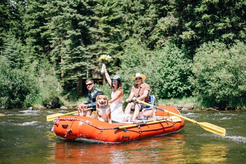 Wedding party whitewater rafting, the bride holding up her bouquet